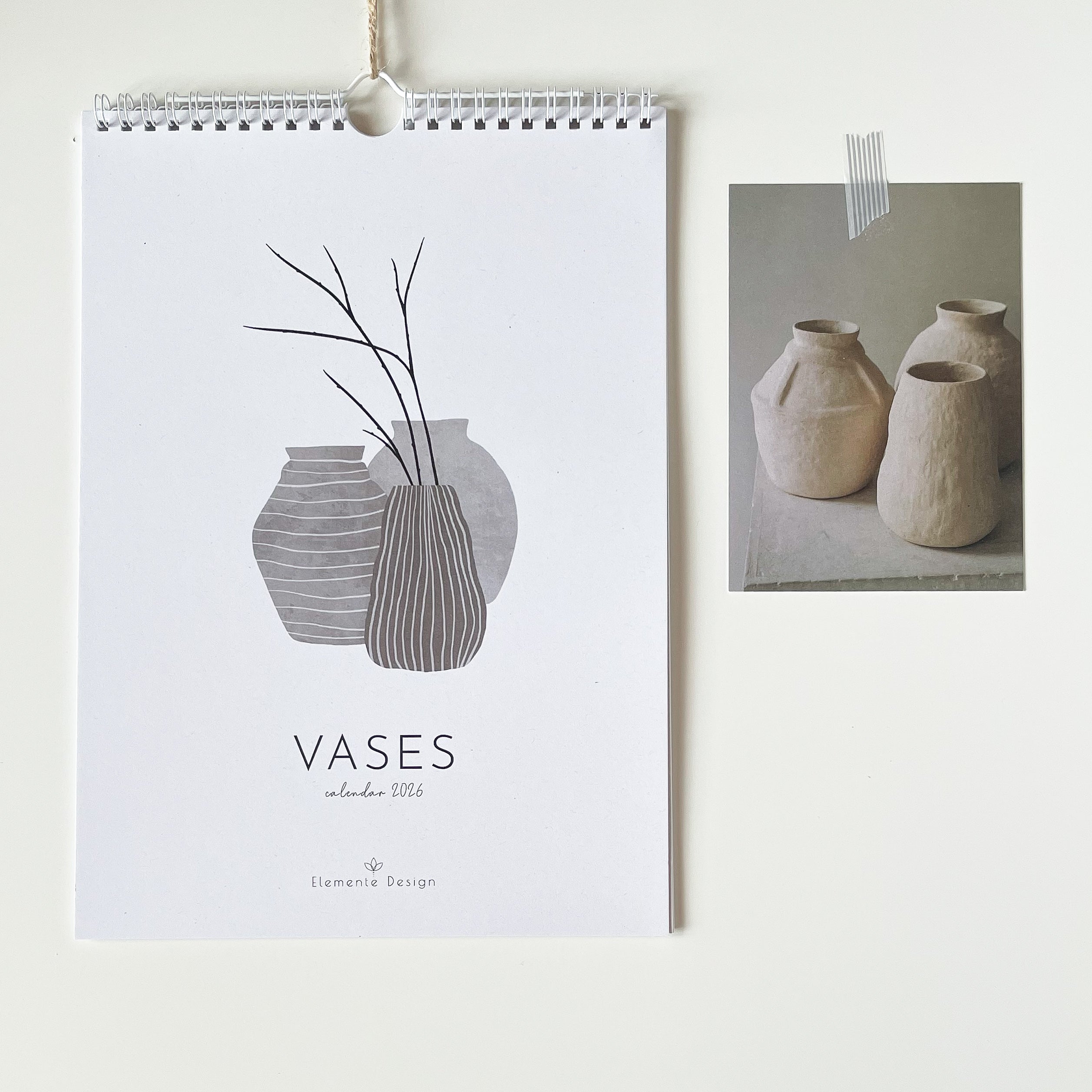 Minimalist calendar 2026 with vase design and a set of photo postcards on a white wall