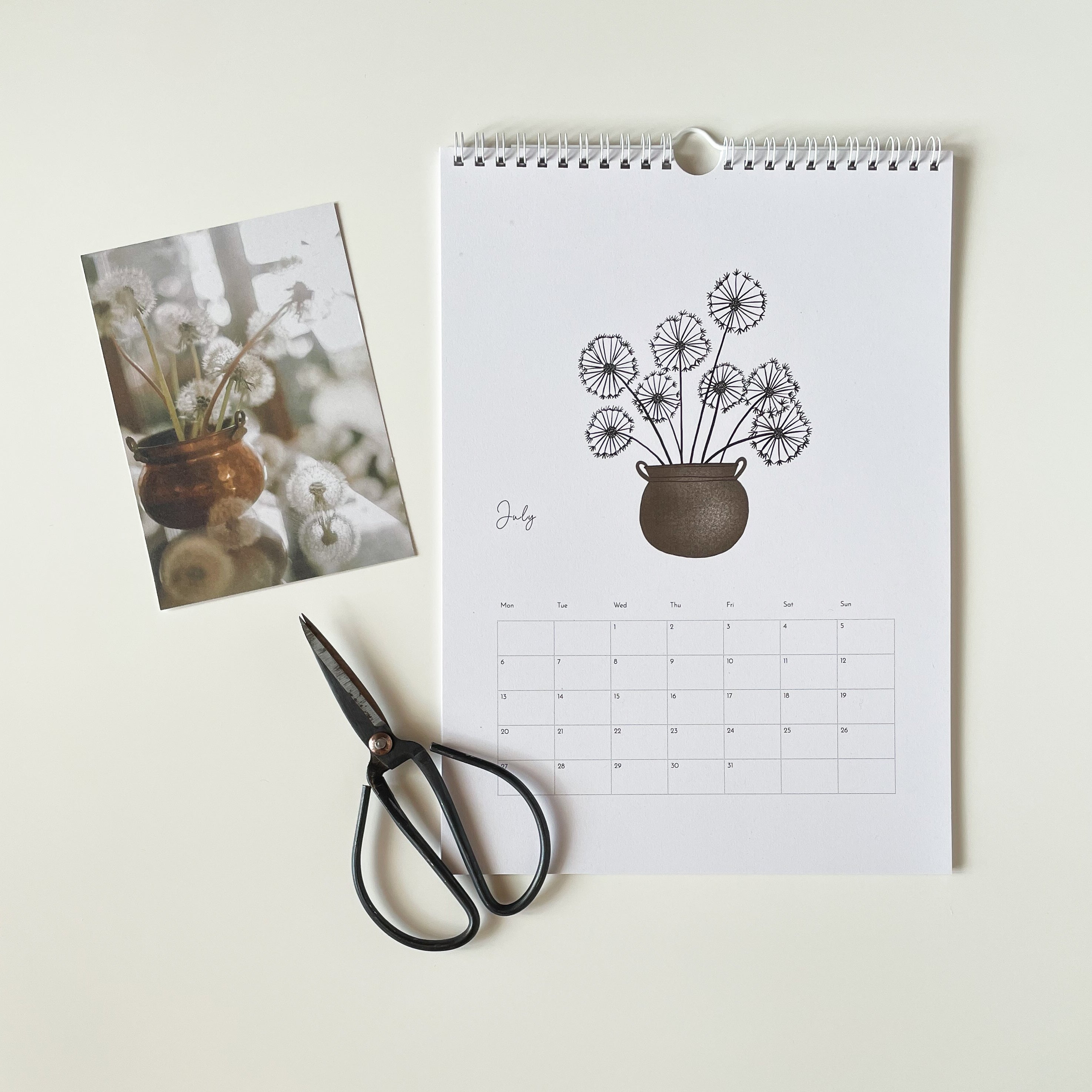 Calendar with floral design, photo of flowers, and scissors on a light background