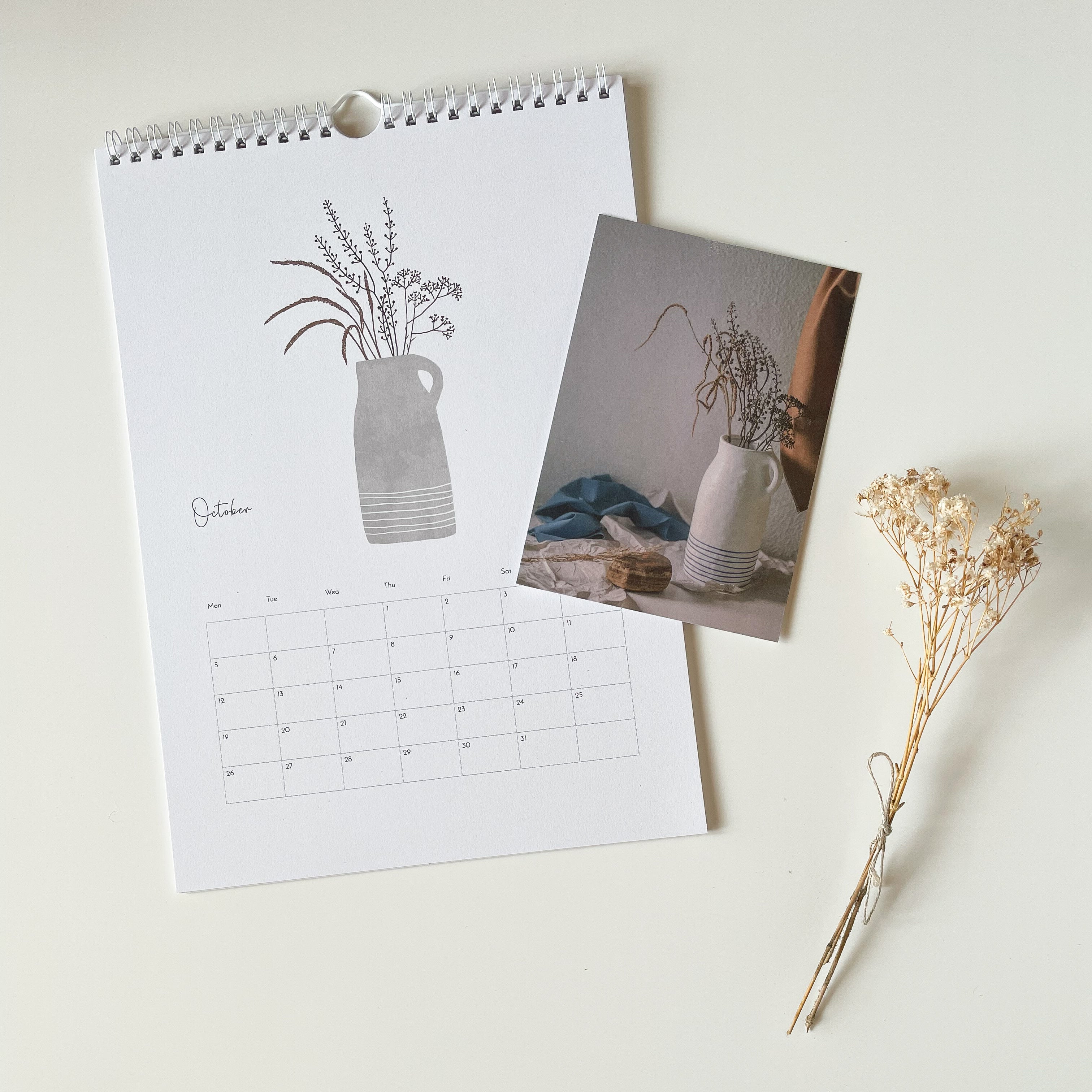 Calendar with a floral design and vase with a photo postcard of a vase with flowers on a light background