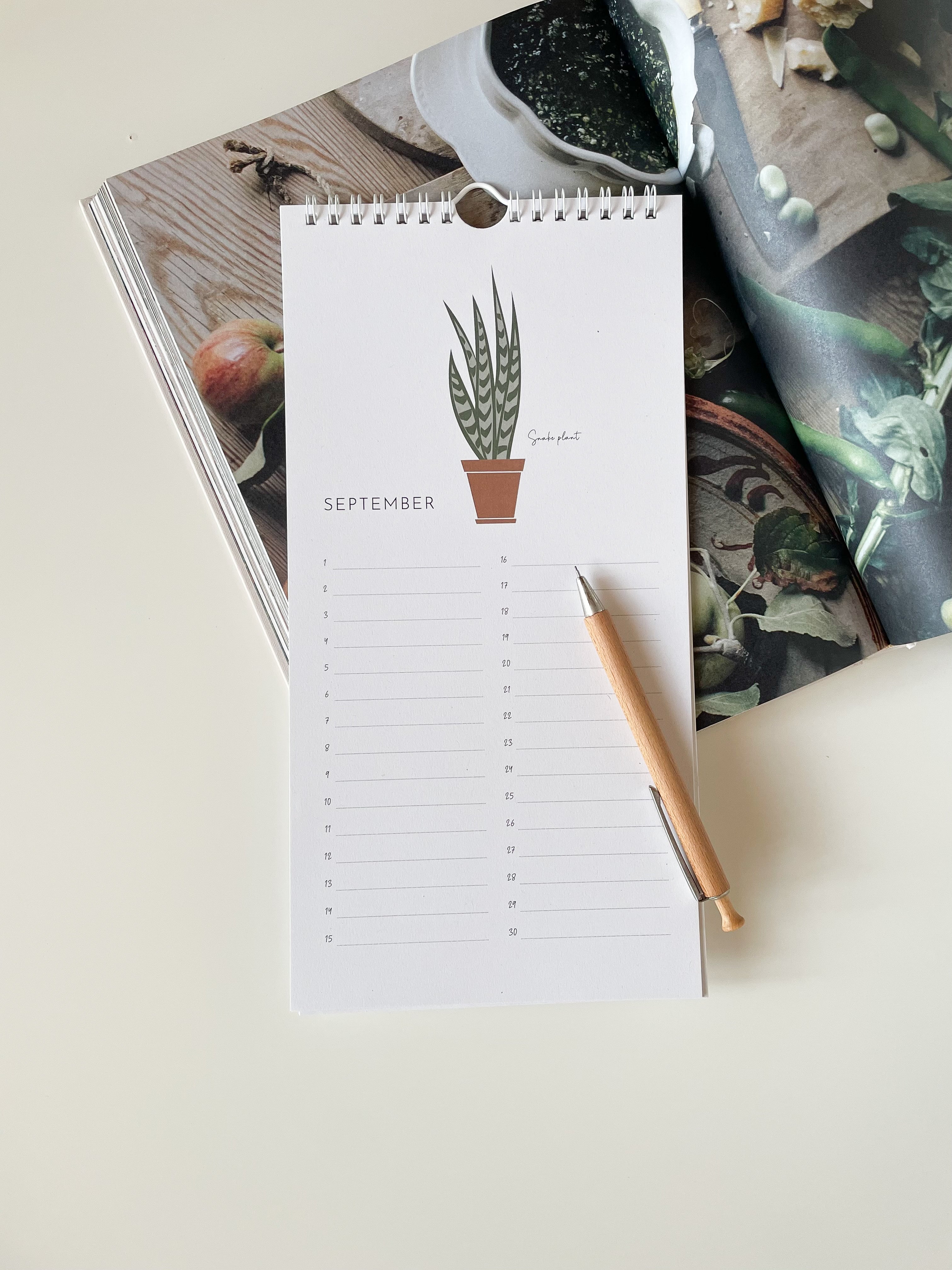 Calendar with a plant illustration on a table with a pen and plant-themed decor