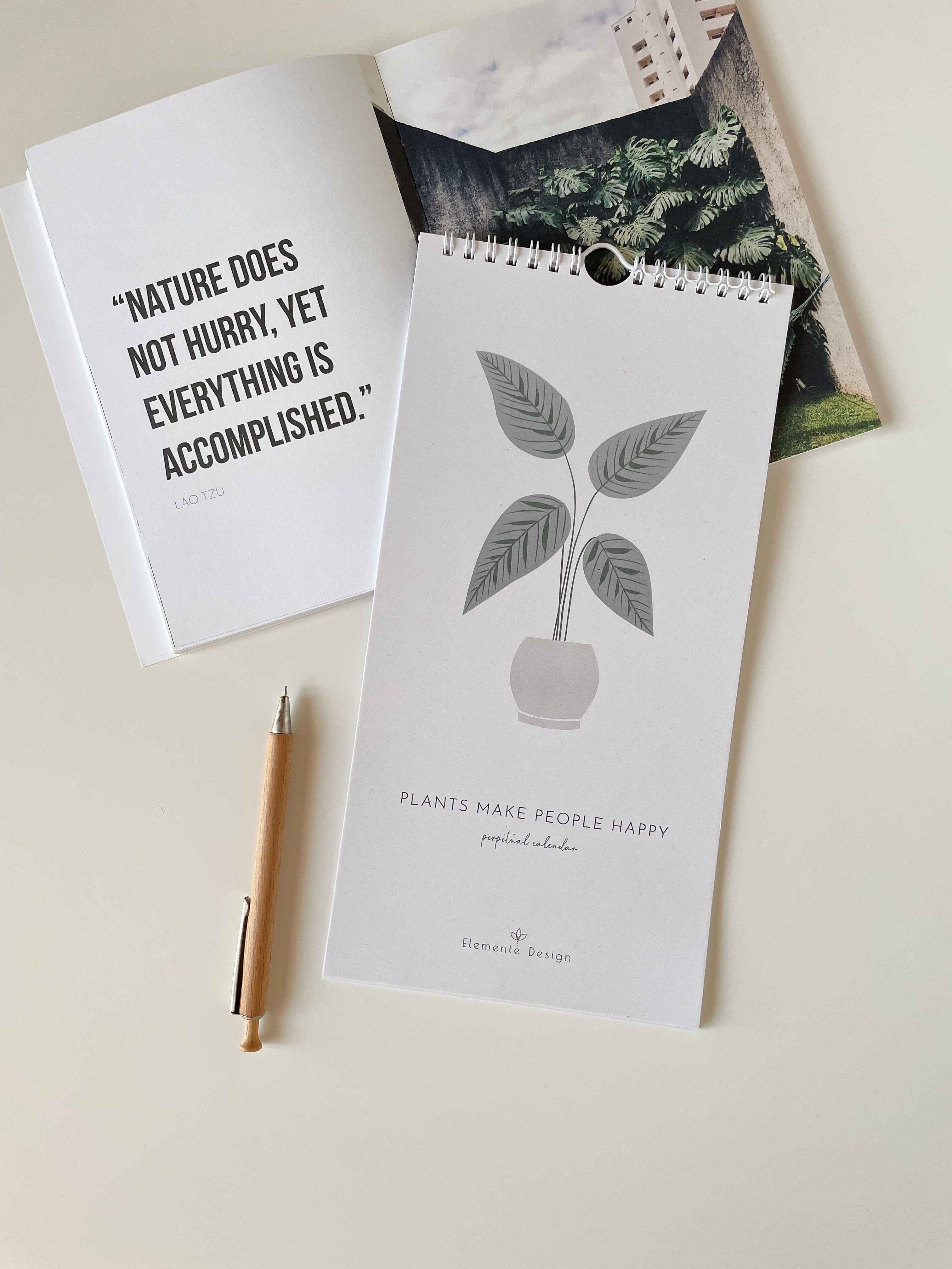 perpetual calendar with plant illustration and text, pen, and magazine on a light surface